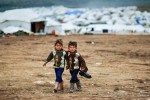 Syrian boys, whose family fled their home in Idlib, walk to their tent, at a camp for displaced Syrians, in the village of Atmeh, Syria, Monday, Dec. 10, 2012
